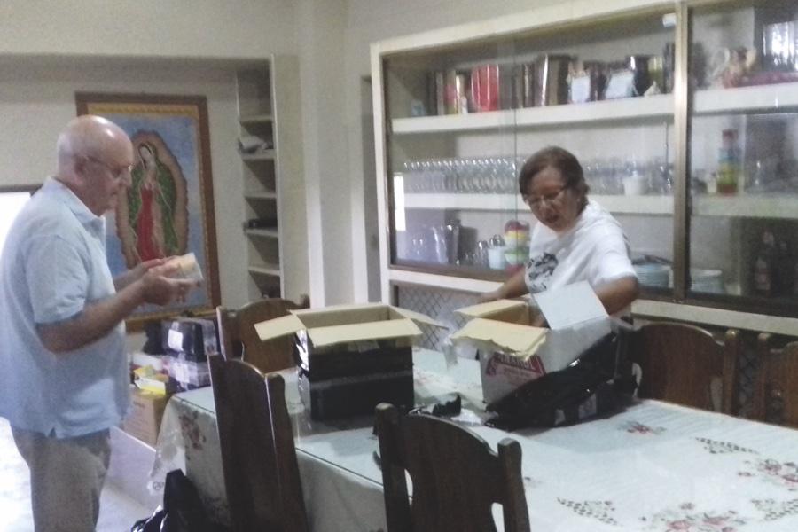 El sacerdote Antonio Collado y la voluntaria Marly Franco ordenan medicinas que reciben de fieles e instituciones en Caicara del Orinoco