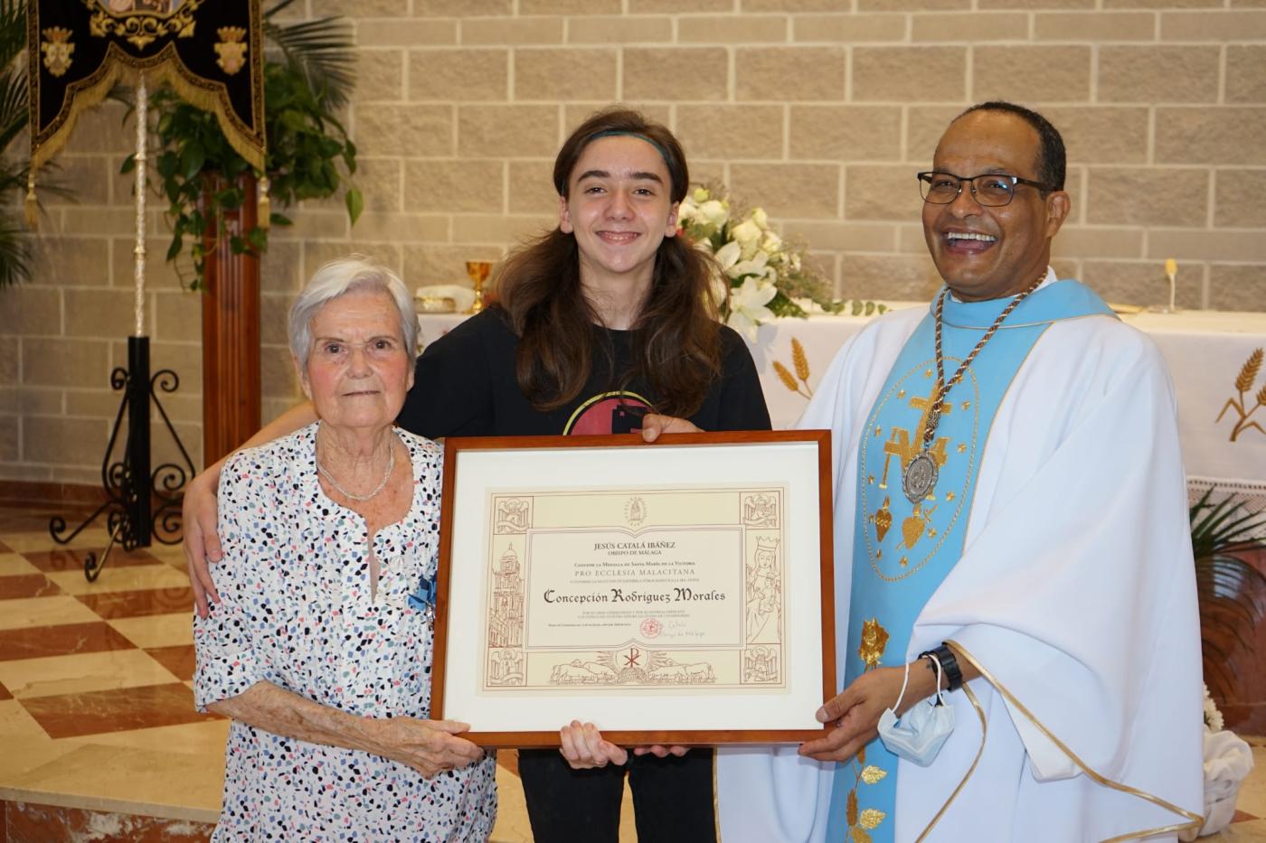 El párroco de Campanillas, Vicente de la Torre, entrega la Medalla Pro Ecclesia Malacitana a Concepción Rodríguez