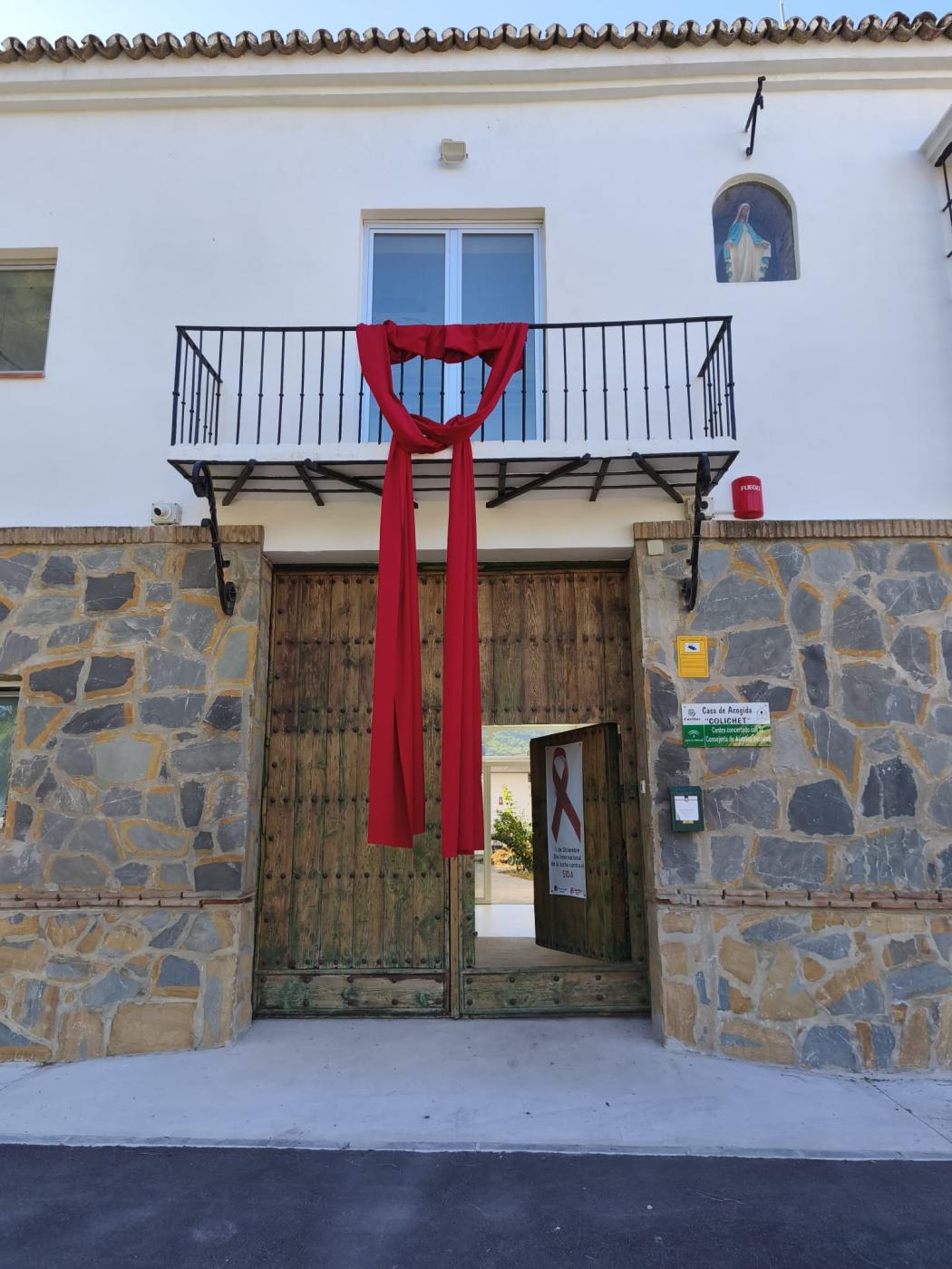 Lazo rojo, símbolo de la lucha contra el sida, colgando de la fachada de la Casa de Acogida Colichet